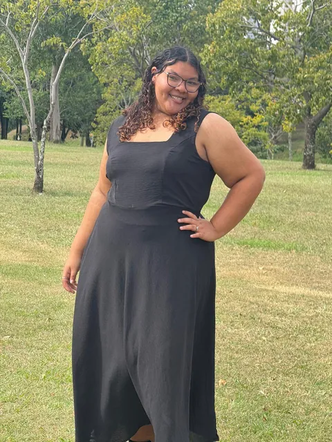 Cliente sorrindo com vestido preto longo feito sob medida pela Tupira