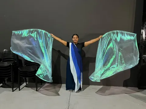 Bailarina com figurino azul e asas de tecido iridescente abertas