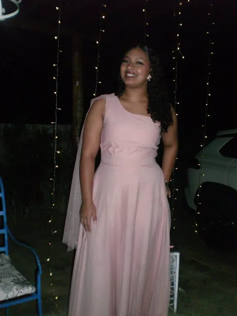Cliente com vestido rosa longo de um ombro só, com véu de tule