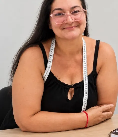Tupira, costureira e modelista do Ateliê Tamareira, sorrindo com uma fita métrica no pescoço